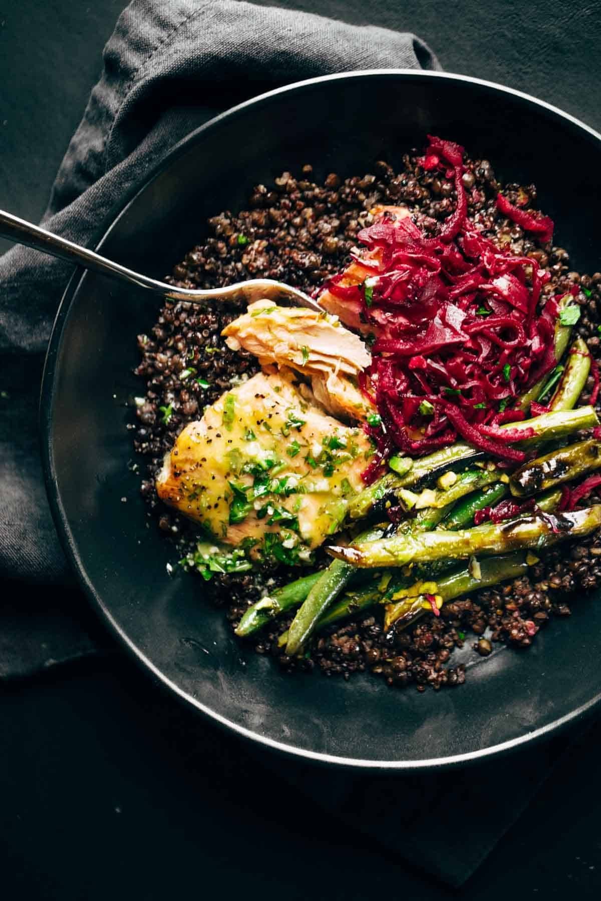 Salmon in a bowl with lentils, green beans, and sauerkraut.