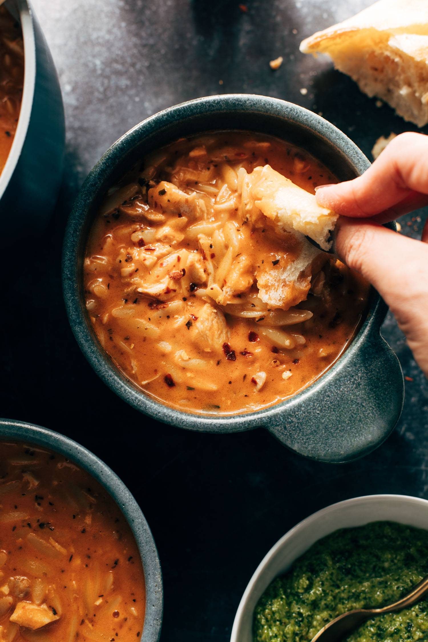 White hand dipping bread into soup